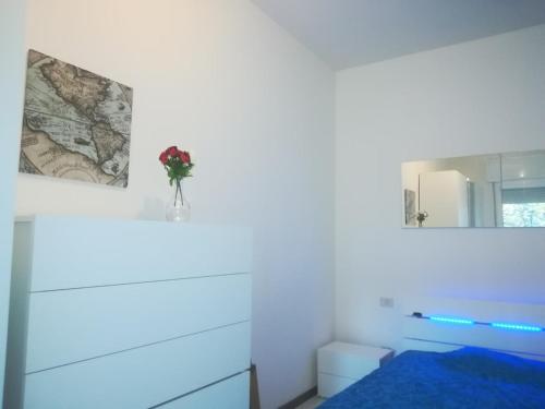 a white bedroom with a bed and a mirror at Bilocale Marina Romea in Marina Romea