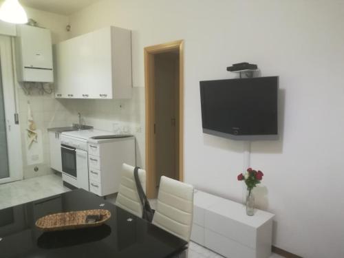 a kitchen with a table and a tv on the wall at Bilocale Marina Romea in Marina Romea