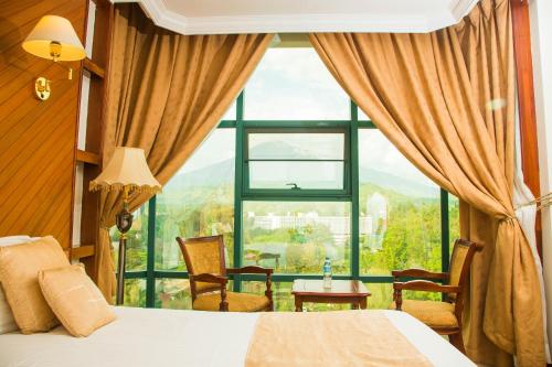 a bedroom with a bed and a large window at Palace Hotel Arusha in Arusha
