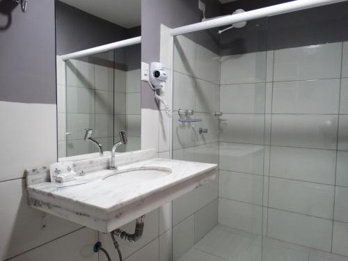 La salle de bains blanche est pourvue d'un lavabo et d'une douche. dans l'établissement Riviera Pantanal Hotel, à Cáceres