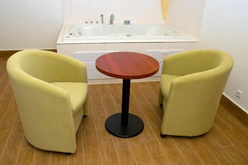 two chairs and a table and a bath tub at Penzion Zlatý vůl in Znojmo