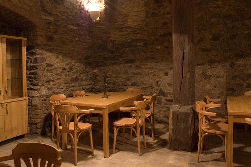 a wooden table and chairs in a room with a stone wall at Penzion Zlatý vůl in Znojmo
