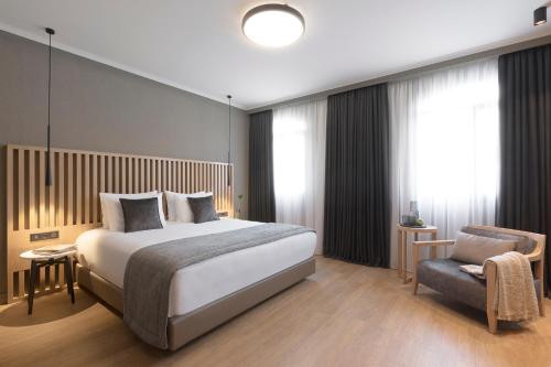 a bedroom with a large bed and a chair at Porto Palace Hotel Thessaloniki in Thessaloniki