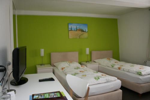 a room with two beds and a desk with a tv at Pension-Ristorante Ventura ehemals Reinhards Pension in Hornburg
