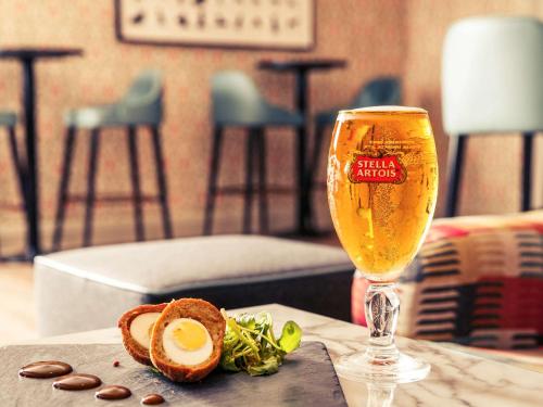 a glass of beer sitting on a table with food at Mercure Maidstone Great Danes Hotel in Maidstone