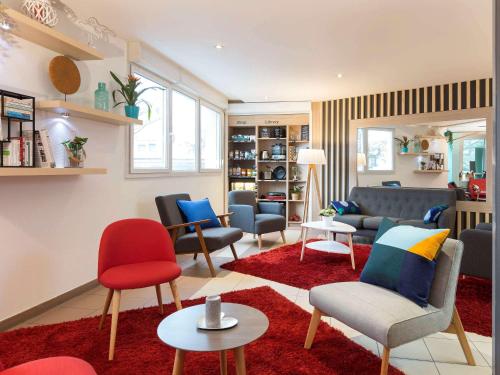 a living room with chairs and couches and tables at Aparthotel Adagio Access Strasbourg Illkirch in Illkirch-Graffenstaden