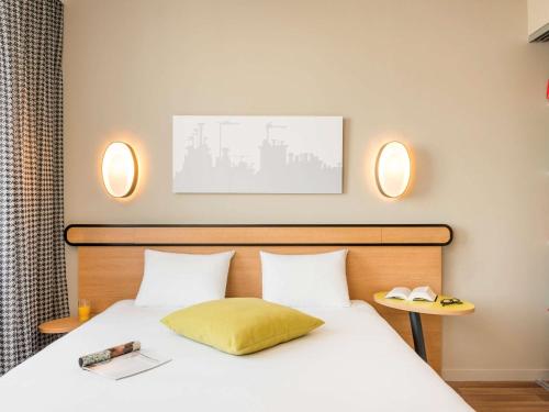 a bedroom with a bed with two lights on the wall at Aparthotel Adagio Access Paris Massy Gare in Massy