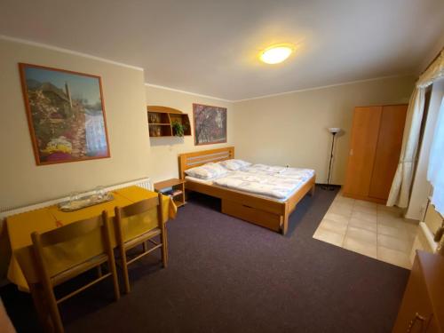 um pequeno quarto com uma cama e uma mesa em Penzion Pod Zámkem em Pruhonice