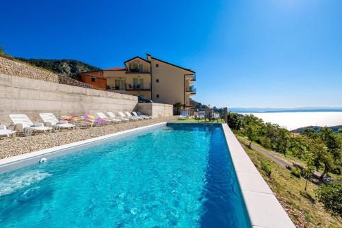 una piscina con sillas y el océano en el fondo en Pansion Villa Betina, en Lovran