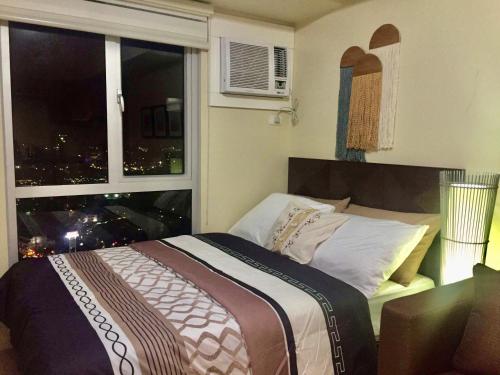 um quarto com uma cama e uma janela com uma cidade em Cozy studio in Cebu IT Park em Cebu