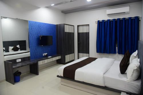 a bedroom with a bed and a tv and blue curtains at Hotel Savera Palace in Ābu Road