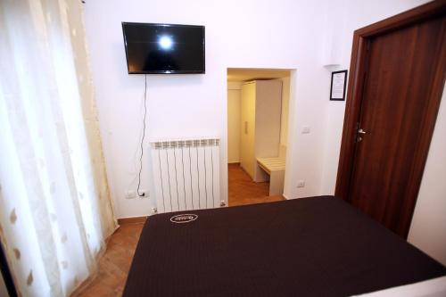 a room with a table and a television on the wall at Orchidea Rooms & Suites in Civitanova Marche