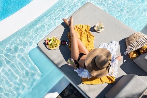 a woman sitting on a towel in a pool of water at Santorini Kastelli Resort in Kamari