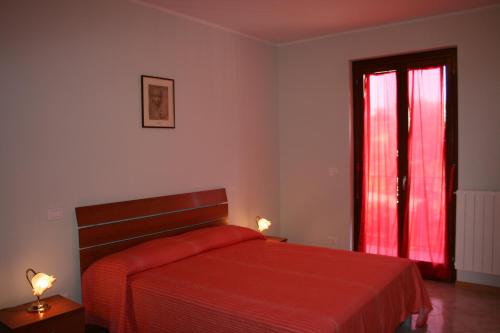 een slaapkamer met een rood bed en een raam bij Casa Fanfulla in Marciano Della Chiana