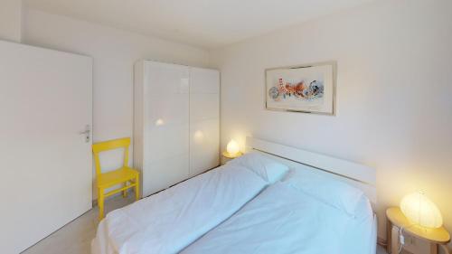 1 dormitorio con 1 cama y 1 silla amarilla en Unique Serviced Living @ Basel Waterfront (9001) en Basilea