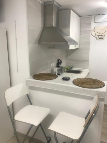 a kitchen with two white chairs and a stove at Estudio La Concepción in Las Lagunas