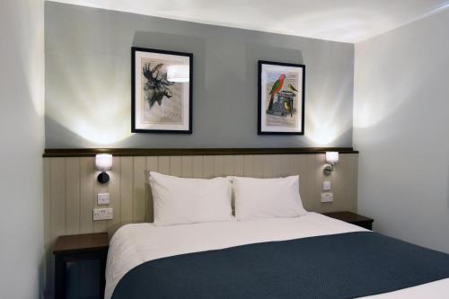 a bedroom with a bed with two pictures on the wall at Oaklands by Greene King Inns in Chester
