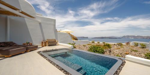 a villa with a swimming pool with a view of the ocean at Neptune Luxury Suites in Akrotiri