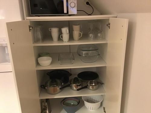 a white cabinet with pots and pans and a microwave at Nordanå Gård in Strö