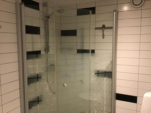 a glass shower in a bathroom with black and white tiles at Nordanå Gård in Strö