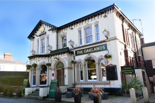 a white building with a sign on the front of it at Oaklands by Greene King Inns in Chester
