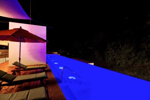 a swimming pool with an umbrella and two chairs and a table at Hotel Puerto Sayulita in Sayulita
