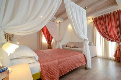 a bedroom with a bed and curtains and a couch at Aeolis Boutique Hotel in Naxos Chora
