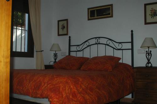 a bedroom with a bed with an orange blanket at Casa Jazmín in Zahora