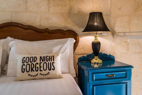 a bed with a blue nightstand with a lamp and a pillow at Valletta Lucente Guest House in Valletta