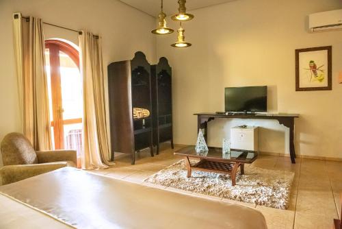 a living room with a tv and a table at Tenondé Park Hotel in São Miguel das Missões