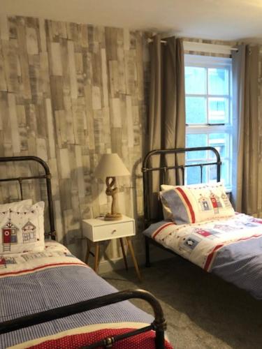 a bedroom with two beds and a window at Fisherman’s Cottage in Y Felinheli