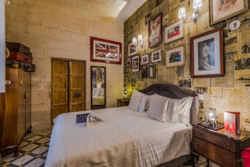a bedroom with a bed and pictures on the walls at Valletta Lucente Guest House in Valletta