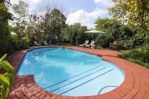 uma grande piscina azul num pátio de tijolos em Whispering Oaks Guest House em George