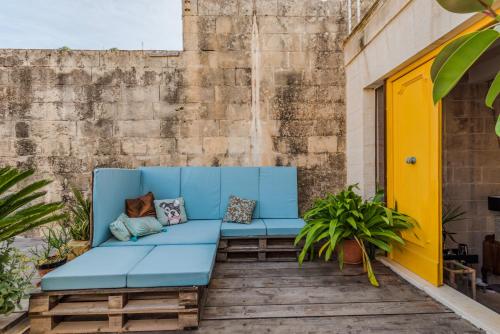 a blue couch on a patio with plants at Valletta Lucente Guest House in Valletta
