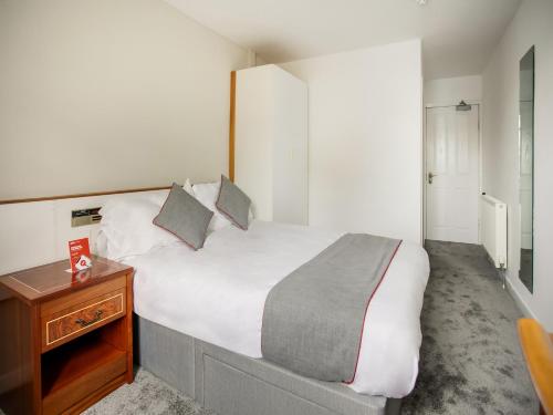 OYO Glenpark Hotel, Ayr Central في آير: غرفة نوم بسرير كبير وطاولة خشبية