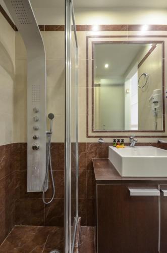 a bathroom with a shower and a sink and a mirror at Aeolis Boutique Hotel in Naxos Chora