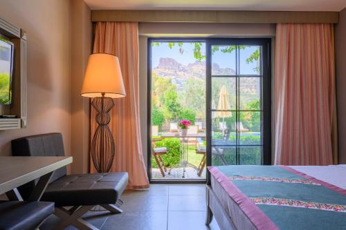 a bedroom with a bed and a desk and a large window at Villa Rustica Hotel in Gundogan