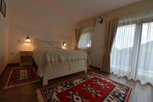 a bedroom with a bed and two windows and a rug at Pensiunea Drumul Plutasilor in Alexandru cel Bun
