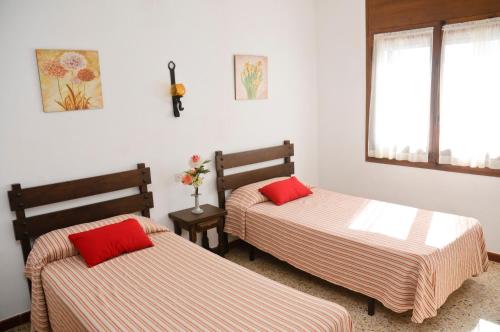 Cette chambre comprend 2 lits avec des oreillers rouges. dans l'établissement RVHotels Apartamentos Villas Piscis, à L'Estartit