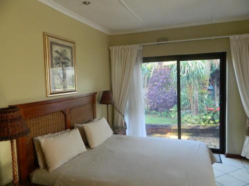 a bedroom with a bed and a large window at Birdcage B&B in Amanzimtoti