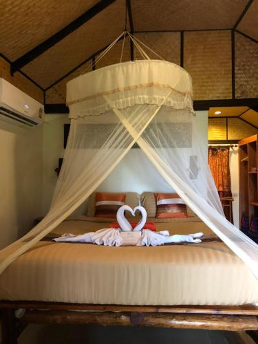 two swans laying on a bed with a canopy at Nautilus Right on the Beach - Adult Only - SHA Extra Plus in Ko Lanta