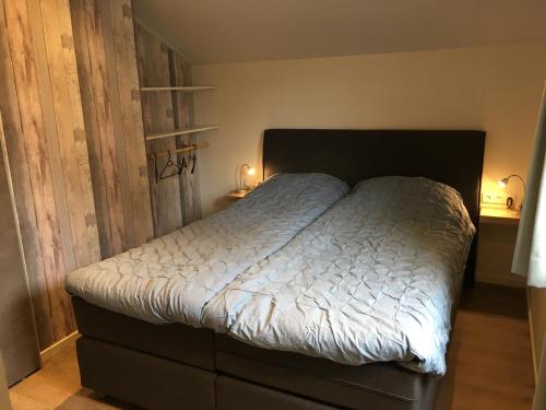 een bed in een slaapkamer met 2 lichten aan bij Vakantiewoning 't Steechje in Hollum