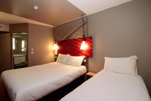 two beds in a small room with white sheets at ibis Cahors in Cahors