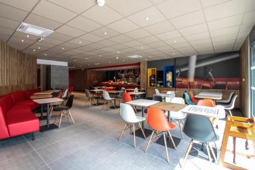 a restaurant with a red couch and tables and chairs at ibis Cahors in Cahors