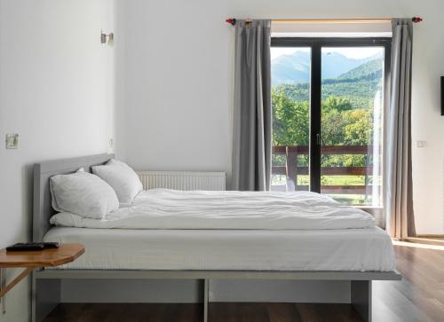 a bed in a bedroom with a large window at Pensiunea ANA Vistisoara in Vistisoara