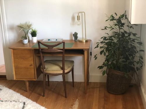 a wooden desk with a chair next to a plant at La Stube de Marinette 5 étoiles in Hipsheim