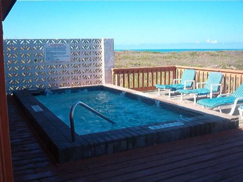 a hot tub on a deck with two chairs at Padre South Hotel On The Beach in South Padre Island