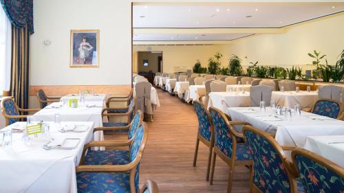 uma sala de jantar com mesas e cadeiras brancas em Alpenhotel Weitlanbrunn em Sillian