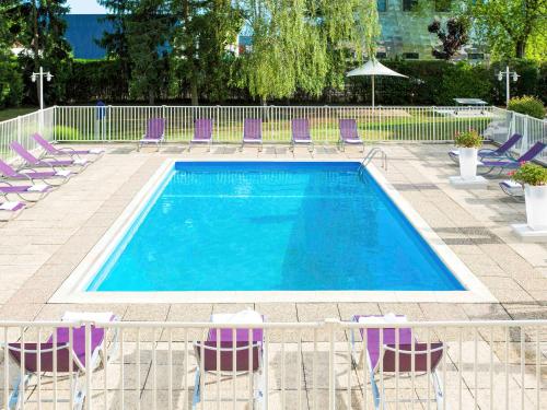 a swimming pool with purple lounge chairs at Novotel Dijon Sud in Marsannay-la-Côte