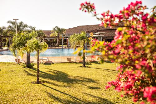 un complejo con piscina, palmeras y flores rosas en Tenondé Park Hotel, en São Miguel das Missões